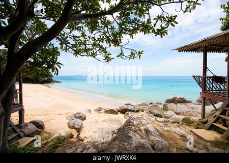 Perhentian Island, perfekt weißen Sandstrand, türkisblaues Meer mit hölzernen Umkleidekabinen am Strand auf Felsen. Stockfoto