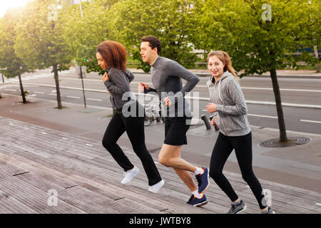 Seitenansicht Portrait von athletischen jungen Menschen in Sportkleidung, läuft draußen auf Stadt Treppen an einem sonnigen Tag Stockfoto