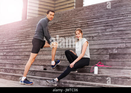 Porträt junger sportlicher Mann und Frau Warming-up zusammen draußen auf Stadt Treppen an einem sonnigen Tag Stockfoto