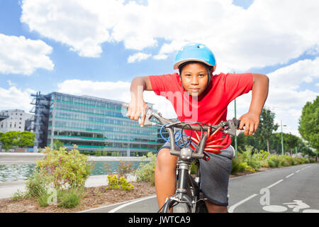 Portrait von Jugendlichen afrikanischen Jungen in Sicherheit Helm reiten sein Fahrrad auf Radweg im Sommer Stockfoto