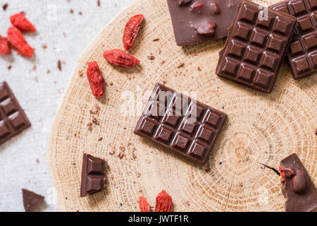 Bars von Raw hausgemachte Schokolade mit goji auf Holz- schicht. Vegetarische Konzept der gesunden Ernährung. Ansicht von oben Stockfoto