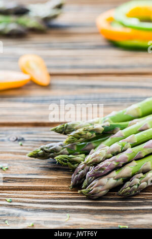 Rohen grünen Spargel, grüner Pfeffer, Scheiben, Cherry Tomaten. Frische Zutaten. Holztisch. Selektiver Fokus Stockfoto