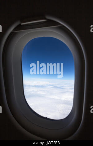 Vertikaler Flugzeug Fenster, weiße Wolken füllen die untere Hälfte des Fenster mit blauen Himmel Vertiefung in Farbe Nach oben Stockfoto