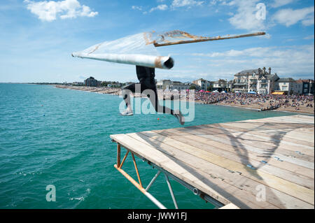 Während der Internationalen Bognor Birdman Ereignis in Chichester, England, einen Mitbewerber vom Ende der Bognor Pier mit einem Hängegleiter springt. Stockfoto