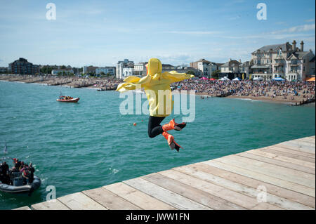 Während der Internationalen Bognor Birdman Ereignis in Chichester, England, einem Wettbewerber in einem gelben Ente Kostüm springt in die siehe am Ende von Bognor Pier in Bognor Regis, West Sussex, England. Stockfoto