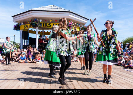 England, Broadstairs Folk Festival. Die Damen Morris Seite, Offcumduns, Tanzen beim Musikpavillon in Broadstairs Meer im Sommer Sonnenschein. Das Tragen von grünen tatter Jacken. Stockfoto