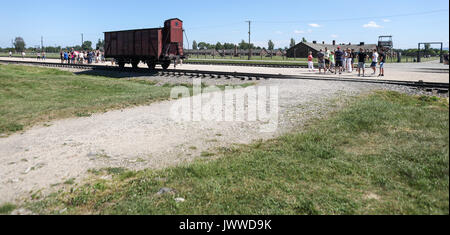 Besucher stehen vor einem Güterwagen auf der berüchtigten Rampe im ehemaligen Konzentrationslager Auschwitz-Birkenau in Oswiecim, Polen, 21. Juni 2017. Die wichtigsten paramilitärischen Organisation im nationalsozialistischen Deutschland, SS (Schutzstaffel, lit. "Schutz Squadron"), lief die Konzentrations- und Vernichtungslager zwischen 1940 und 1945. Eingehende Deportierten wurden in verschiedene Gruppen, die auf der Rampe zwischen den Tracks ausgewählt, nachdem Sie in Birkenau angekommen. Die Menschen, die nicht in der Lage waren zu arbeiten (ältere Menschen, Menschen mit schwachen, Frauen, Kinder) waren manchmal zu den Gaskammern direkt ohne Registrierung gesendet. Etwa 1,1 bis 1,5 Stockfoto