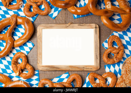 Oktoberfest Konzept mit Rahmen mock up und auf hölzernen Hintergrund Brezel. Blick von oben. Flach Stockfoto