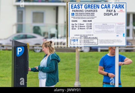 Frau Geld in einem Parkplatz Maschine ein Ticket an eine kostenpflichtige Parkplatz in Großbritannien zu kaufen. Stockfoto