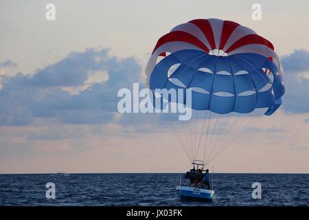 Ein Boot ziehen einer Parasail im düsteren Blick auf Boracay Meer. Gleitsegeln ist eine der vielen Aktivitäten, die Sie in diesem beliebten Reiseziel tun können. Stockfoto