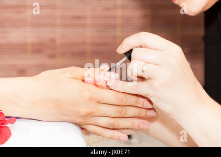 Festlegung Nagellack auf die Hände einer Frau Stockfoto