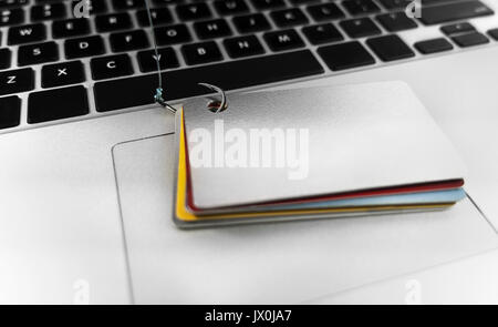 Identität Diebstahl - Kreditkarte phishing. Computer Laptop mit Kreditkarten und Angeln Haken. Stockfoto