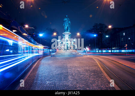 Lichtstreifen durch Bewegungsunschärfe eines öffentlichen Nahverkehrs, der nachts in Berlin unterwegs ist und sein geschäftiges Nachtleben und den Transport zeigt Stockfoto