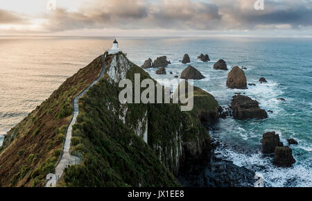 Sonnenaufgang am Nuggets Leuchtturm, die Catlins, Neuseeland. Schöne Landschaft mit gefährlichen Felsen und stürmischen Wolken im Hintergrund. Stockfoto