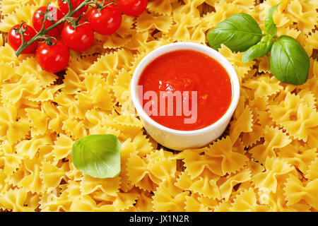 Ungekocht Bow Tie Pasta mit Tomatensauce. Stockfoto