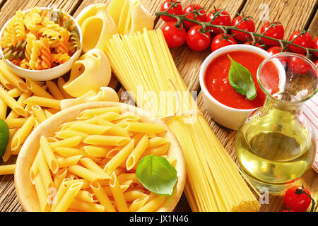 Verschiedene Pasta, Tomaten passata und Olivenöl auf hölzernen Hintergrund Stockfoto