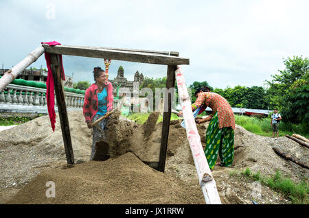 Zwei Mädchen Arbeiter Sand, der auf den verdrahteten Netz, combodian Kloster, lumbini Peace Garden, Nepal Stockfoto