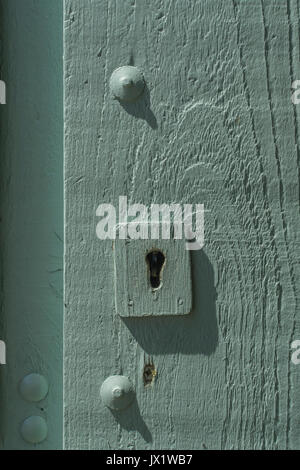 Schlüsselloch in einem blassen aschengrün lackierten Holzgartentor. Metapher für "gesperrt" oder Daten-/E-Mail-Privatsphäre, Anmeldesicherheit, Sperrung. Stockfoto