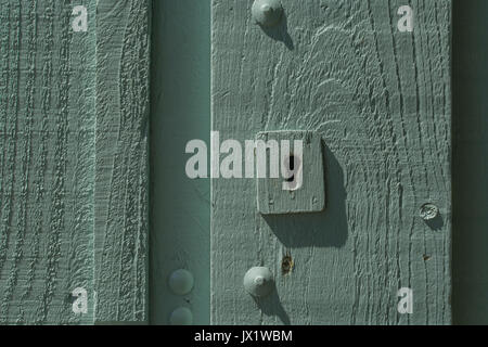Schlüsselloch in einem blassen aschengrün lackierten Holzgartentor. Metapher für "gesperrt" oder Daten-/E-Mail-Privatsphäre, Anmeldesicherheit, Sperrung. Stockfoto