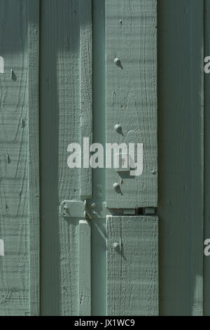 Schlüsselloch in einem blassen aschengrün lackierten Holzgartentor. Metapher für "gesperrt" oder Daten-/E-Mail-Privatsphäre, Anmeldesicherheit, Sperrung. Stockfoto