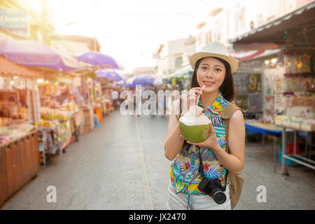 Berühmte weibliche Blogger nach Thailand reisen Verkostung lokaler beliebte Coconut Wasser auf dem schwimmenden Markt Amphawa Straße zu gehen und die Bilder auf Stockfoto