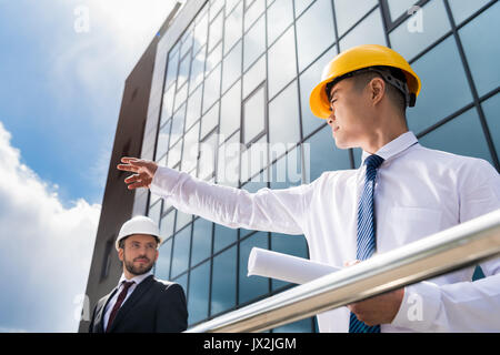 Low Angle View von professionellen Architekten in harte Hüte diskutieren Projekt, erfolgreiche Geschäftsleute Konzept Stockfoto