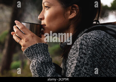 Close Up Side Shot von jungen asiatischen weiblichen Wanderer Kaffee zu trinken. Weibliche Wanderer Rest nehmen während der Wanderung. Stockfoto