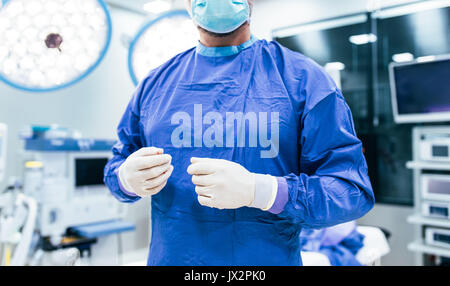 Nahaufnahme von Arzt Tragen von OP-Handschuhen und Peelings in Betrieb Theater. Chirurg bereit für den Einsatz im Krankenhaus. Stockfoto