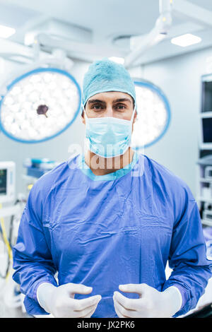 Porträt der Chirurg das Tragen von OP-Handschuhen und Peelings in Betrieb Theater. Arzt in Scrubs und medizinische Maske im Krankenhaus OP-Saal. Stockfoto