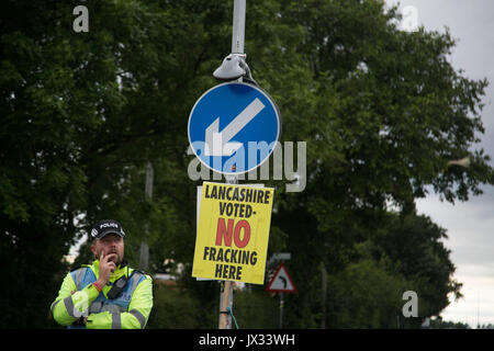 Ein Polizist stand unter einer anti-fracking Zeichen durch die Tore von Quadrilla fracking Website in Lancashire. Stockfoto