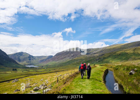 Wanderer Wandern entlang einer gewaehrleistung Wasserlauf mit Blick entlang Ogwen Tal in den Bergen von Snowdonia National Park. Ogwen, Conwy. North Wales, Großbritannien, Großbritannien Stockfoto