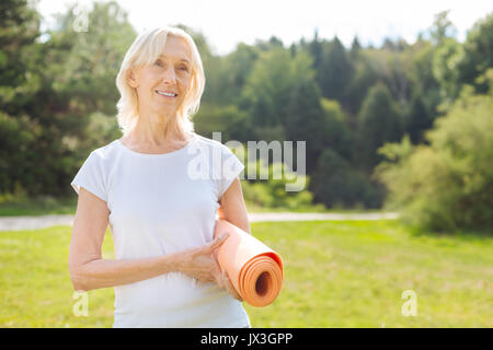 Positiv erfreut ältere Frau ihre matte Holding Stockfoto