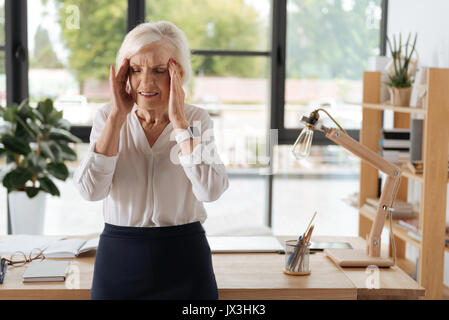 Traurige ältere Frau leidet unter Migräne Stockfoto