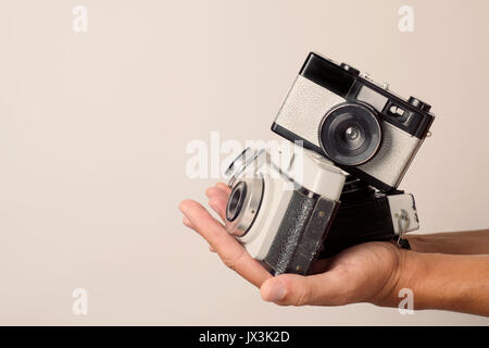 Nahaufnahme von einem jungen Mann mit einem Stapel von alten Film Kameras in seine Hände, gegen einen weißen Hintergrund mit einem leeren Raum auf der linken Seite Stockfoto