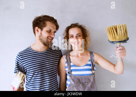 Schöne junge Paar in Liebe, Spaß, Malerei Mauern ihres neuen Hauses mit Pinsel. Home Makeover und Sanierungskonzept. Stockfoto