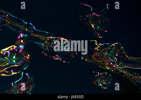 Bubble Gebläse macht Seifenblasen gegen den schwarzen Himmel Hintergrund Stockfoto