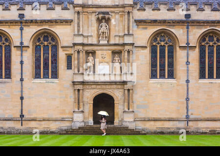 Wadham College, eine der konstituierenden Colleges der University of Oxford Parks Road, Oxford im August auf einem nassen regnerischen Tag wie Frauen gehen mit Sonnenschirmen Stockfoto