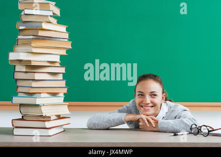 Glückliche junge Kursteilnehmer mit Stapel Bücher. Foto von jugendlich Schülerin im Klassenzimmer, kreatives Konzept mit Zurück zum Thema Schule Stockfoto