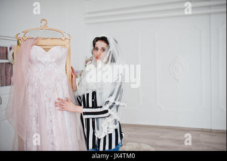 Porträt einer fabelhaften jungen Braut posieren mit ihrem Kleid in einem großen, hellen Raum. Stockfoto