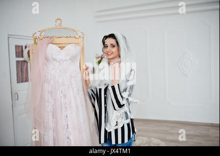 Porträt einer fabelhaften jungen Braut posieren mit ihrem Kleid in einem großen, hellen Raum. Stockfoto