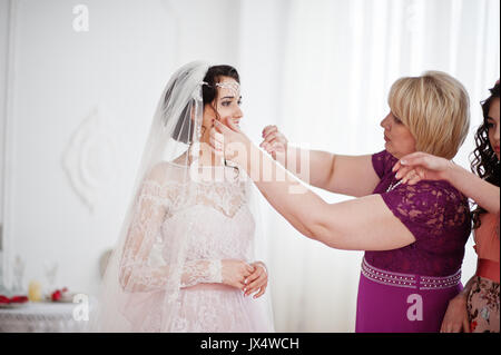 Brautjungfern und Mutter helfen Braut zu verkleiden und machen Sie sich bereit für ihre Hochzeit. Stockfoto