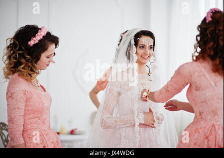 Brautjungfern und Mutter helfen Braut zu verkleiden und machen Sie sich bereit für ihre Hochzeit. Stockfoto