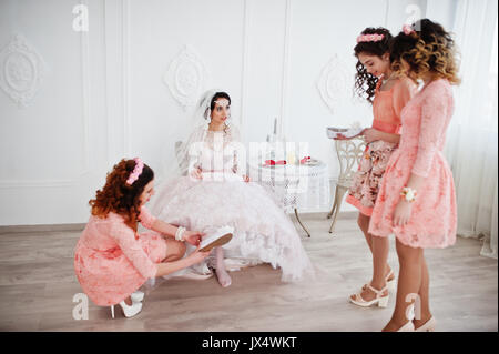 Brautjungfern helfen Braut ihren Schuhe auf und machen Sie sich bereit für ihre Hochzeit. Stockfoto