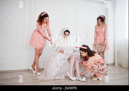 Brautjungfern helfen Braut ihren Schuhe auf und machen Sie sich bereit für ihre Hochzeit. Stockfoto