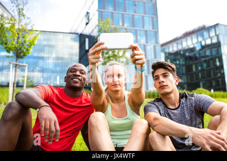 Schöne junge Läufer zusammen in die Stadt nehmen selfie mit smart phone vor Glas Gebäude. Stockfoto