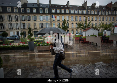 Caen, Calvados in der Normandie, Frankreich. Mann im Regen mit französischen Sticks. August 2017 Mann trägt französische Baguettes unter einem Regenschirm in einer regen Sturm in der cen Stockfoto