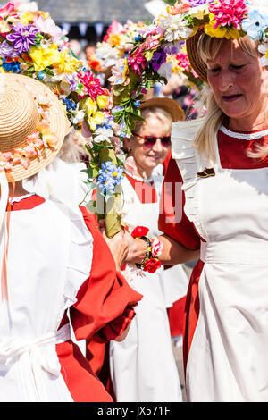 England, Broadstairs Folk Festival. Steigende Lerchen Morris Seite Tanzen draußen im hellen Sonnenschein mit Leute zu beobachten. Holding Halbkreis Girlanden aus Blumen, sie tragen orange Kleidern mit weißen Schürzen auf. Stockfoto