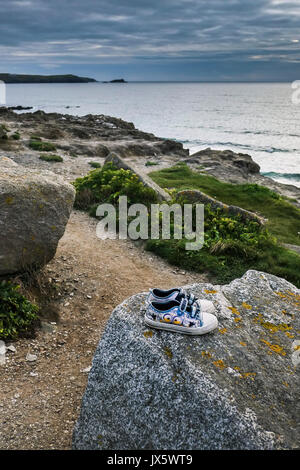 Ein paar Kinder Trainer hinter sich gelassen auf einem Felsen im Little Fistral in Newquay, Cornwall. Stockfoto