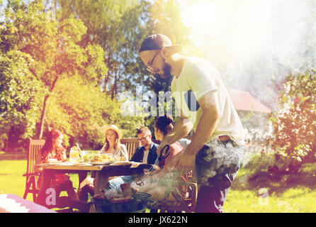 Mann, Kochen von Fleisch auf Grill am Sommerfest Stockfoto