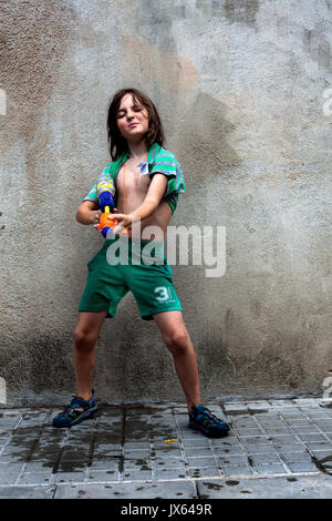 Wunderschöne 8 Jahre alte Junge spielt mit Wasserpistole in der Straße. Stockfoto